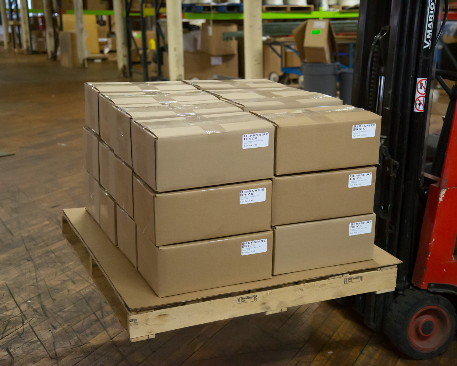 Organized stack of boxes filled with about 46 brick tiles in each box. The brick boxes are stacked on top of a wooden pallet ready to ship to a customer.