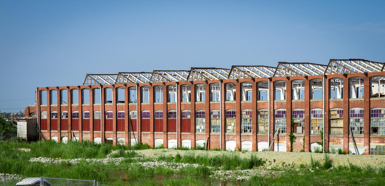 Old brick mill building part of the berkshire hathaway mill complex in new bedford, MA. The buildings roof has been removed and windows on the third floor. The brick exterior frame or bones are still standing strong.