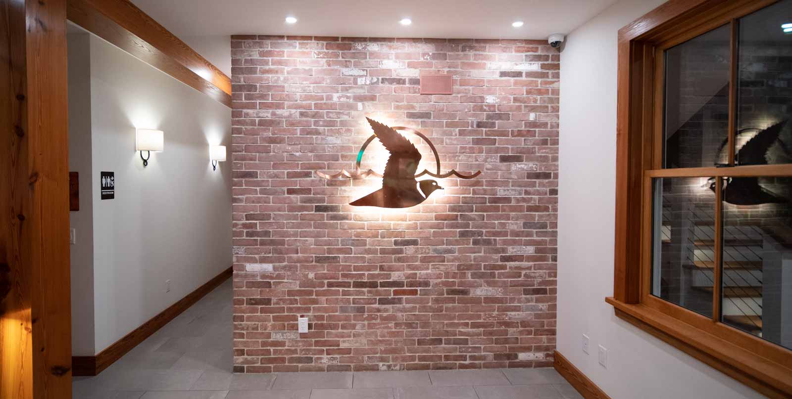 Completed reclaimed brick wall inside customers retail store lobby. Metal sign logo is mounted to the wall and led backlit. All bricks were sourced by Whaling City Brick